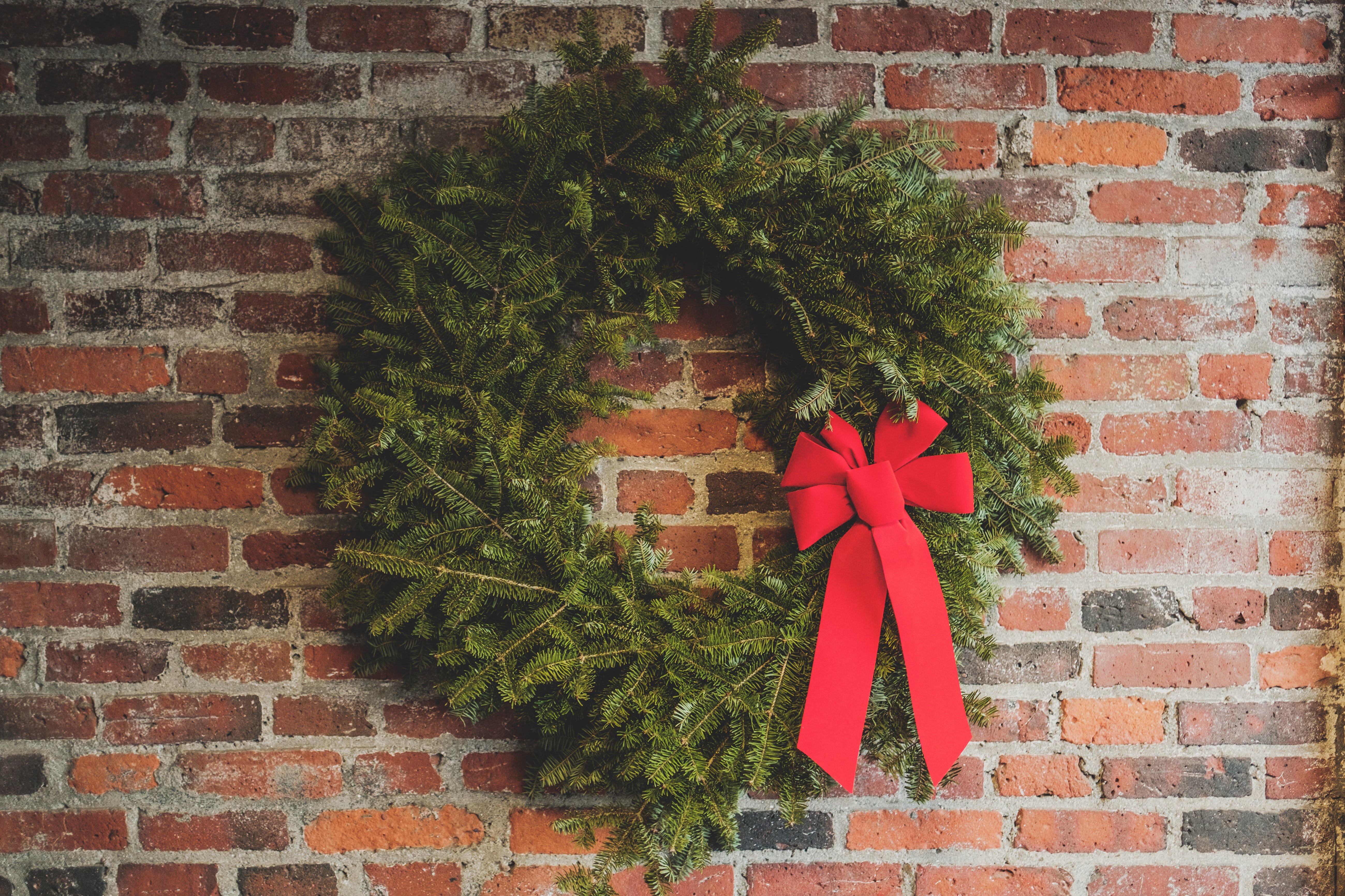 Photo of a Christmas wreath hanging on a brick wall