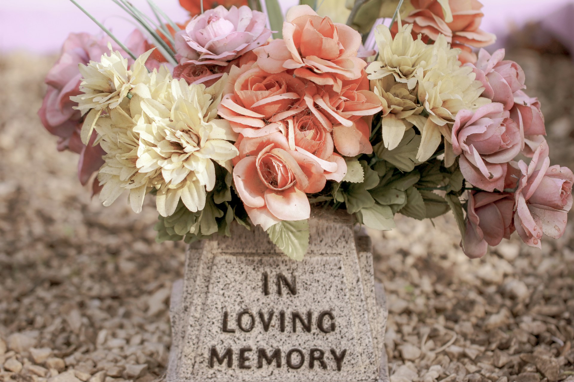 Flowers on top of a gravestone that reads In Loving Memory