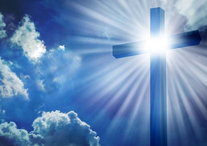 Image of a cross backlit by the sun against a blue sky