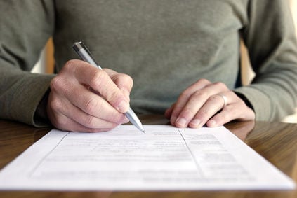 Photo of someone's hands writing on a form