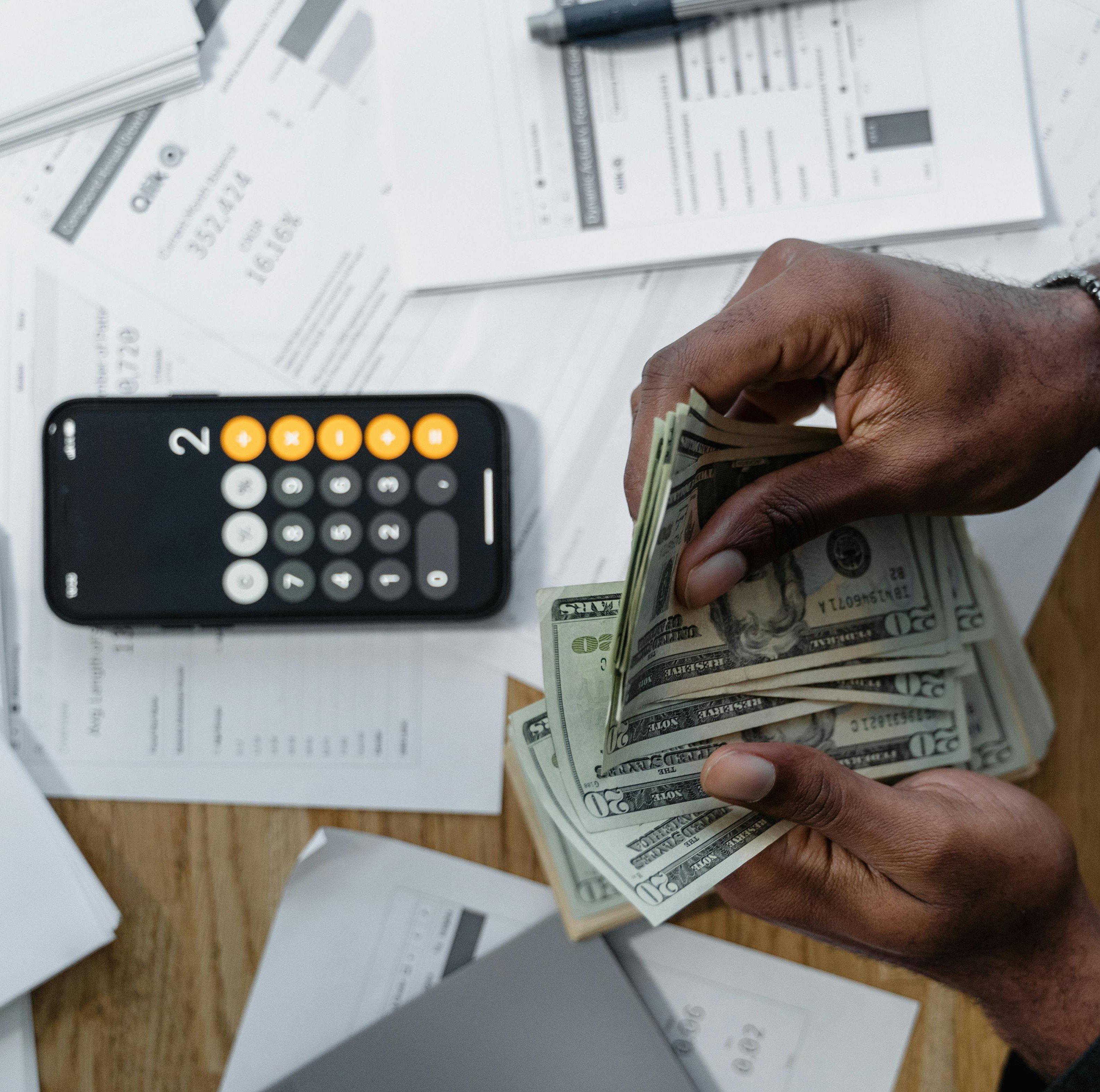 Photo of a calculator and hands counting money