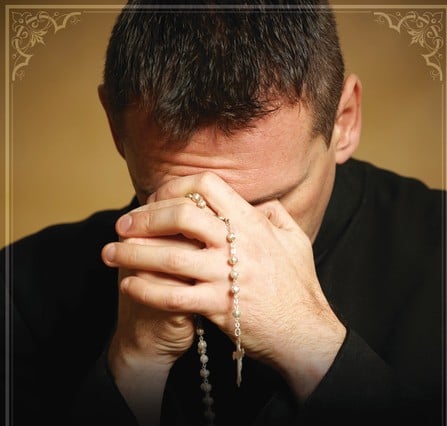 Man with bent head praying the rosary